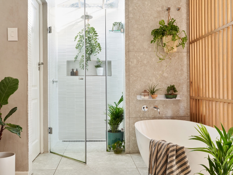 Beige-themed modern bathroom with indoor plants and a glass shower.